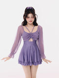 Woman wearing a purple ruched long-sleeve swim dress with a cut-out and flared skirt