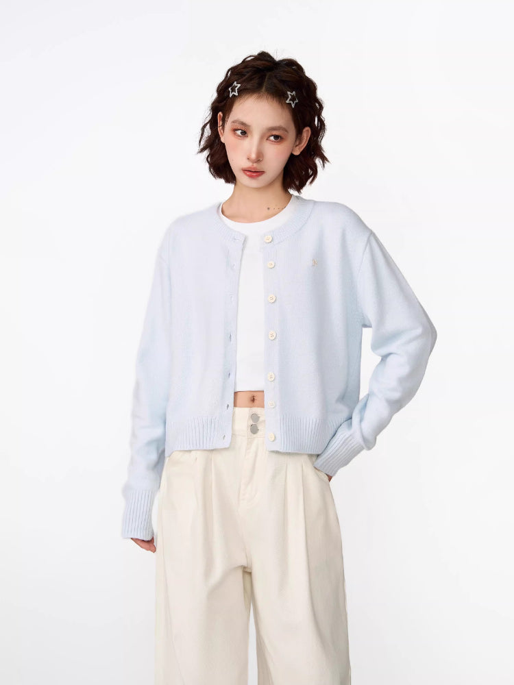 Woman wearing a light blue cropped knit cardigan with a crew neckline and button-front closure.