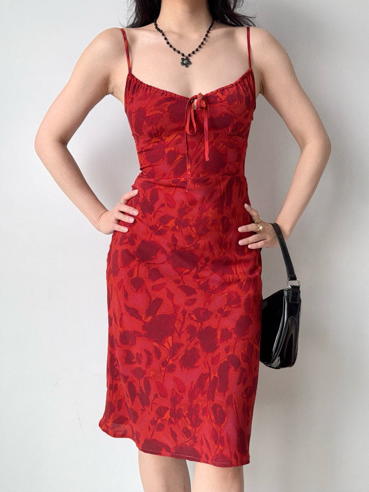 Woman wearing a red floral print midi dress with spaghetti straps and a self-tie front