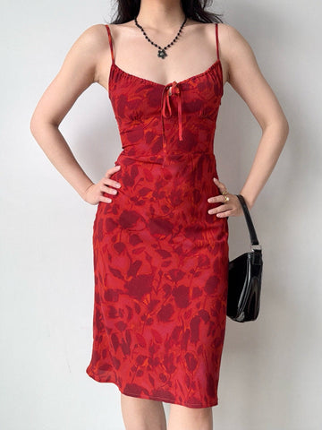 Woman wearing a red floral print midi dress with spaghetti straps and a self-tie front