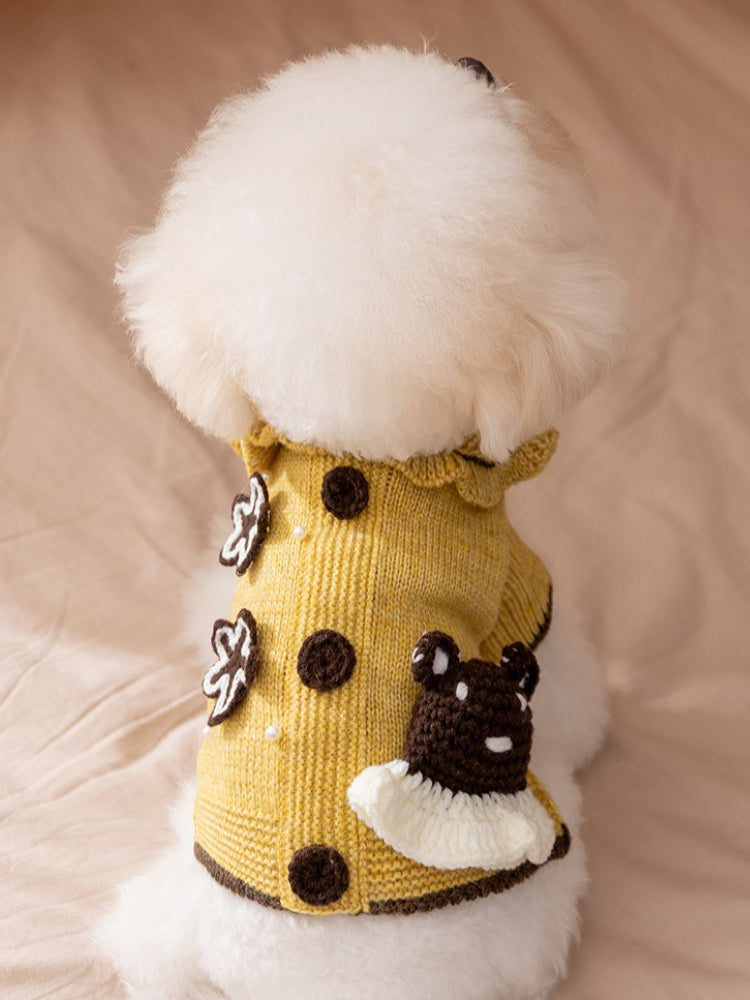 Yellow knitted pet sweater with ruffled collar and brown trim on a white dog.