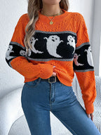 Close-up of a woman adjusting her orange knit sweater featuring a ghost print.
