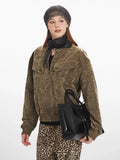 Woman posing with a black handbag, wearing a brown crushed velvet bomber jacket