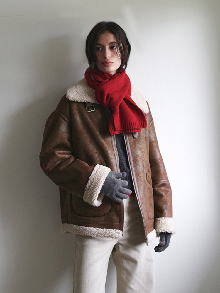 Woman wearing a red knit scarf and a brown aviator jacket