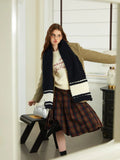 Woman in a tan blazer and plaid skirt wearing a navy and white striped knit scarf.