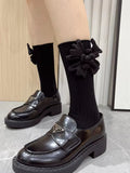 detailed shot of black ribbed knee-high socks adorned with a fabric flower on each leg