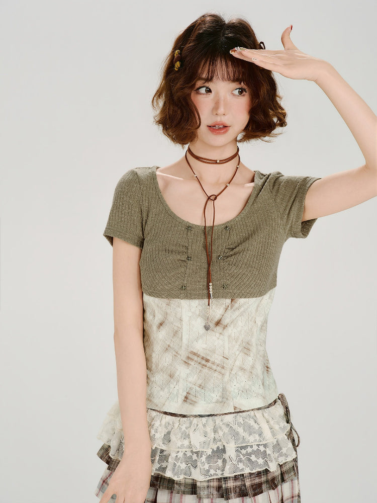 Woman posing in a green ribbed knit top with a scoop neckline and a layered patterned skirt.