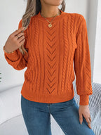 Front view of a woman in an orange knit sweater, showcasing the intricate cable and openwork stitching.