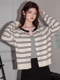 Front view of a woman in a striped knit cardigan, showing the button closure and contrast trim.