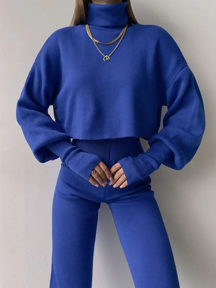 Front view of a woman in a royal blue knit outfit, featuring a turtleneck crop top and high-waisted pants.