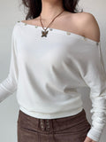 Close-up of the white off-the-shoulder top showcasing the fabric and button accents.