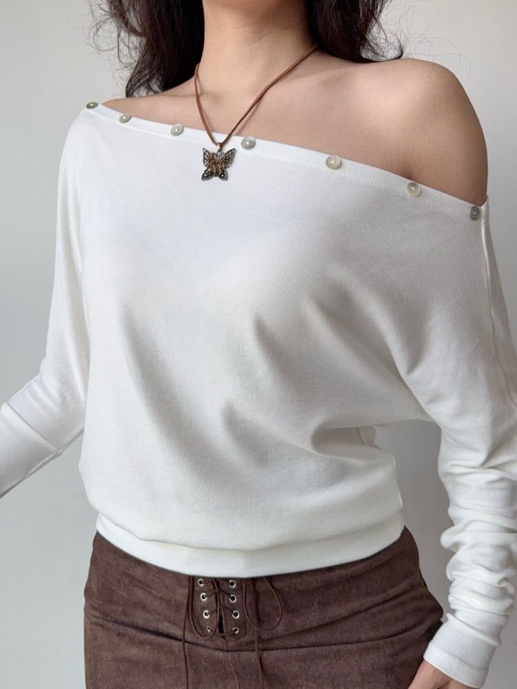 Close-up of the white off-the-shoulder top showcasing the fabric and button accents.