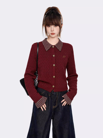 Woman wearing a burgundy cable knit cardigan with a plaid collar and cuffs, paired with dark wash wide-leg jeans.