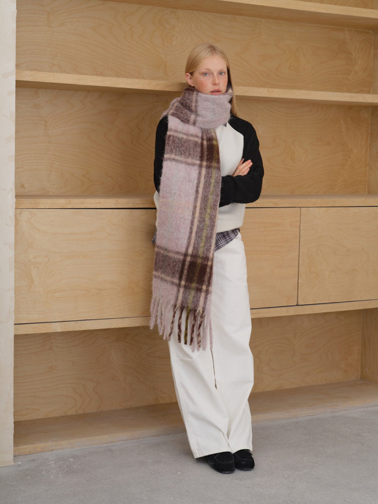 Woman with a large plaid scarf wrapped around her neck.