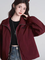 Close-up of a woman in a maroon bomber jacket, showing the zipper and collar.