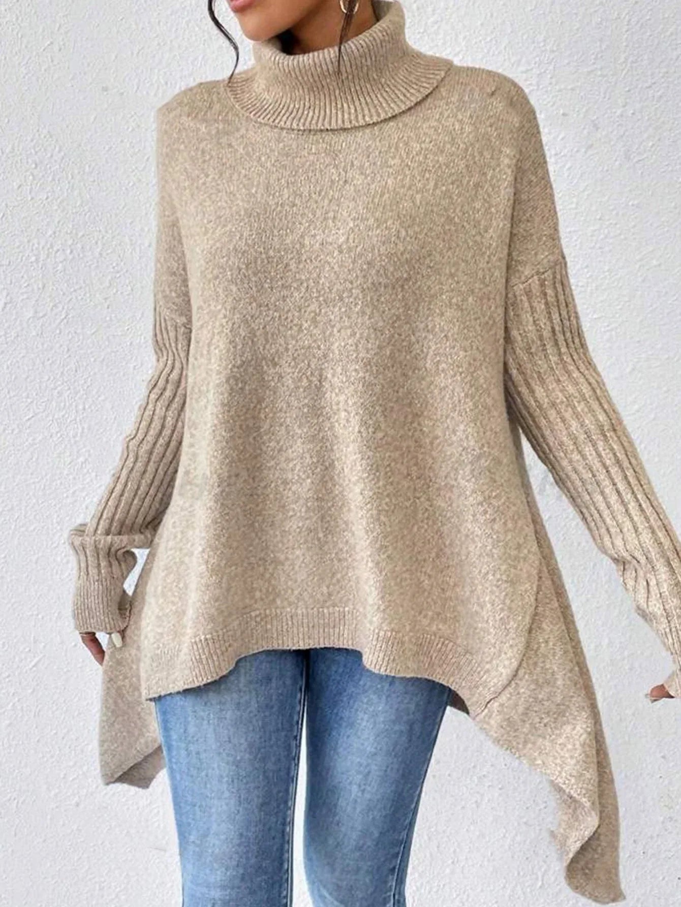 Front view of a woman in a beige knit turtleneck tunic, styled with denim jeans.
