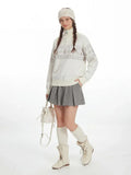 Front view of a woman in a cream-colored Fair Isle knit sweater with a half-zip neckline.