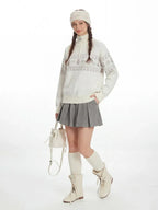 Front view of a woman in a cream-colored Fair Isle knit sweater with a half-zip neckline.