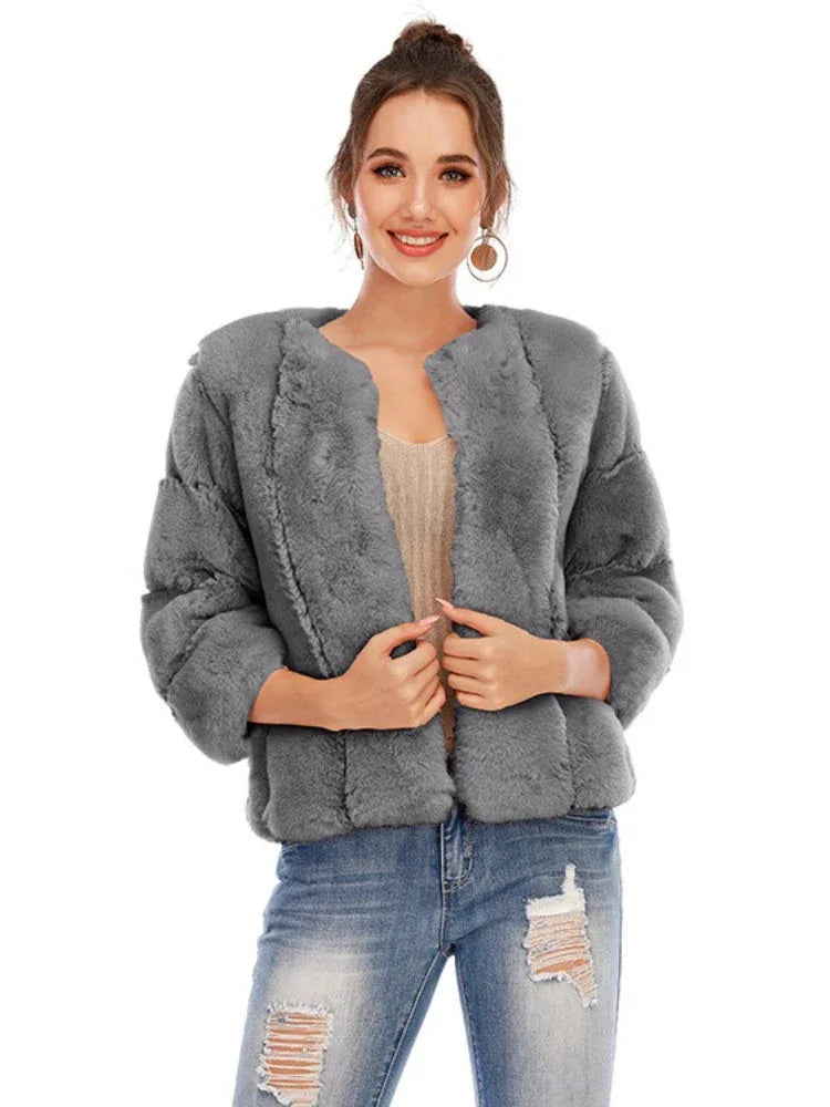Woman wearing a grey faux fur jacket with an open front and textured sleeves.