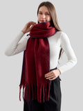 Woman wearing a burgundy knit scarf with fringed ends and blue contrast stitching.