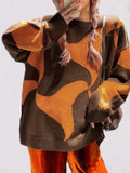Close-up of a woman's torso wearing a brown and orange abstract patterned knit sweater.