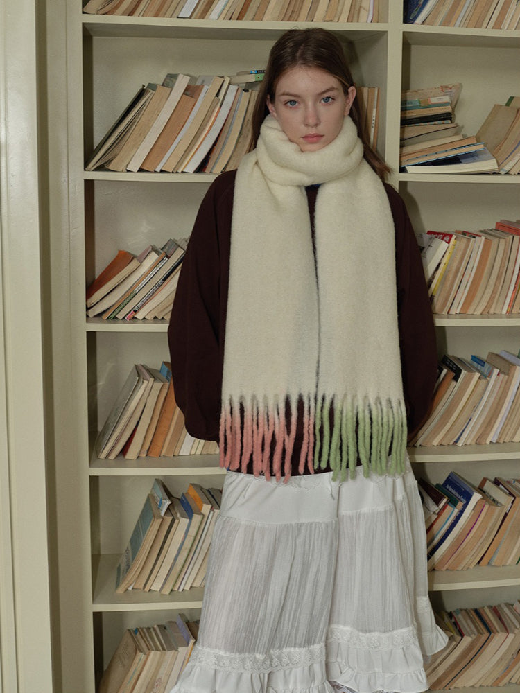 Close-up of a woman wearing a cream scarf with ombre fringe detail.