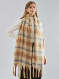 A woman posing with a cozy plaid scarf in neutral tones