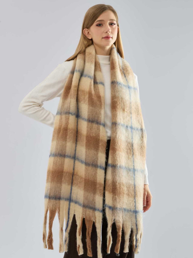 A woman posing with a cozy plaid scarf in neutral tones