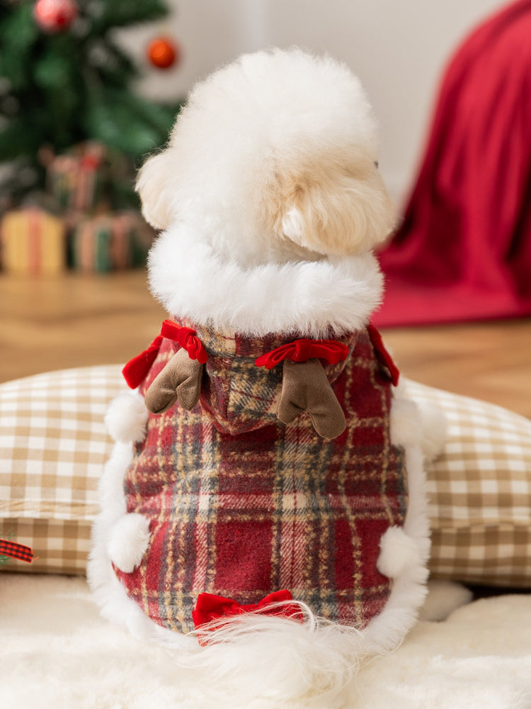Back view of a white dog in a festive red plaid pet coat with faux fur trim and antler details