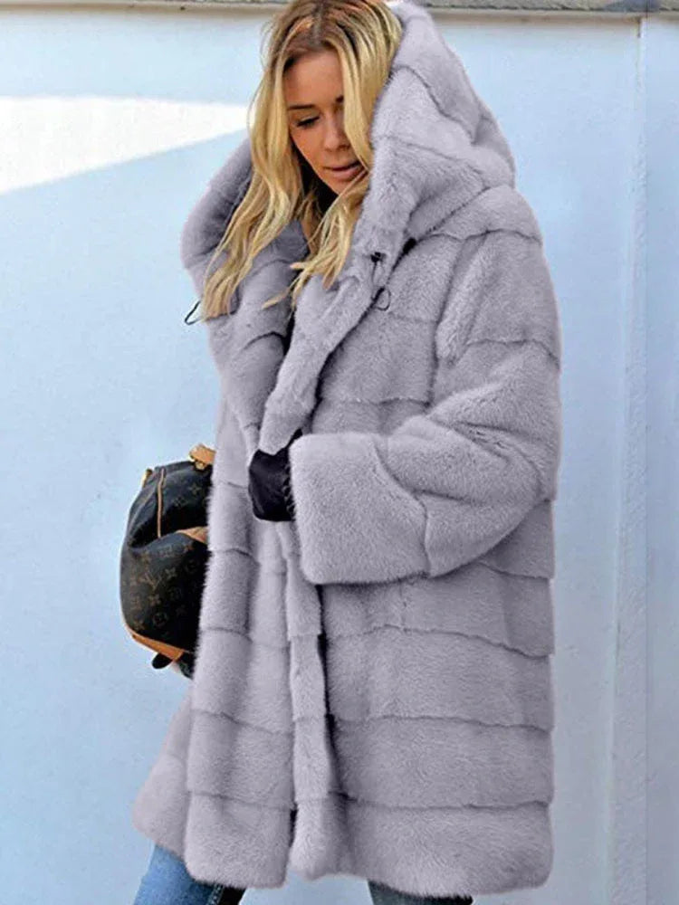 Woman wearing a light grey hooded faux fur coat with horizontal paneling.