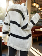 Back view of a woman wearing a white and black striped oversized knit cardigan, showing the full stripe pattern.