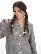 Model adjusting a grey knitted cardigan with decorative pendant