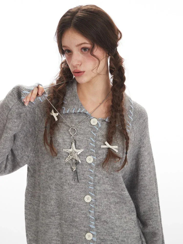 Model adjusting a grey knitted cardigan with decorative pendant