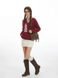 Side profile of a woman in a burgundy V-neck sweater and white skirt, showcasing the outfit.