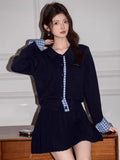 Front view of a woman in a navy knit cardigan with blue gingham detailing on the collar and cuffs.