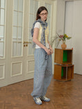 Side profile of a woman in a casual ensemble, with focus on the pants and the draped scarf.