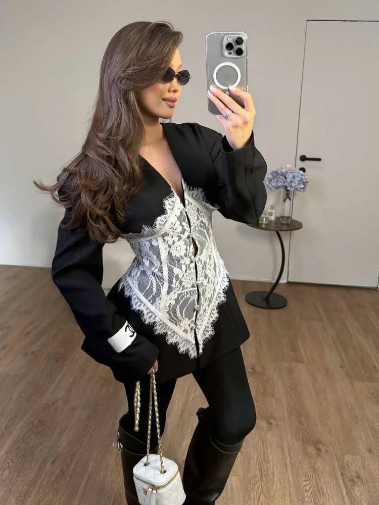 Woman wearing a black blazer dress with a white lace corset overlay and black leggings