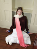 Model wearing a long, fuzzy knit scarf with a cream to pink ombre gradient and fringe trim.