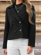 Woman wearing a black double-breasted cropped jacket with notched lapels.