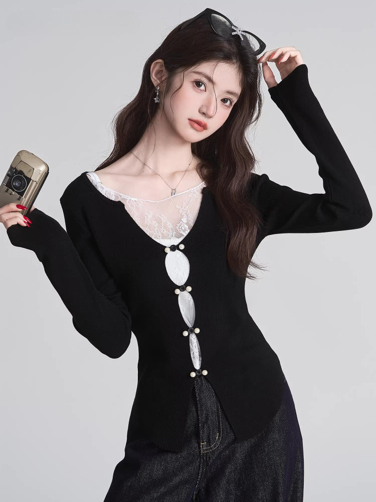 Woman wearing a black knit V-neck long sleeve top with lace trim and decorative buttons