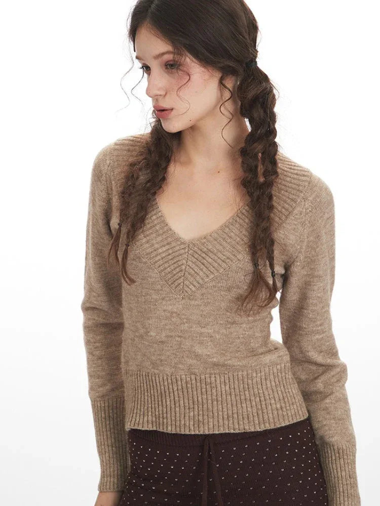 Detailed close-up of the V-neckline and knit texture of the beige sweater.