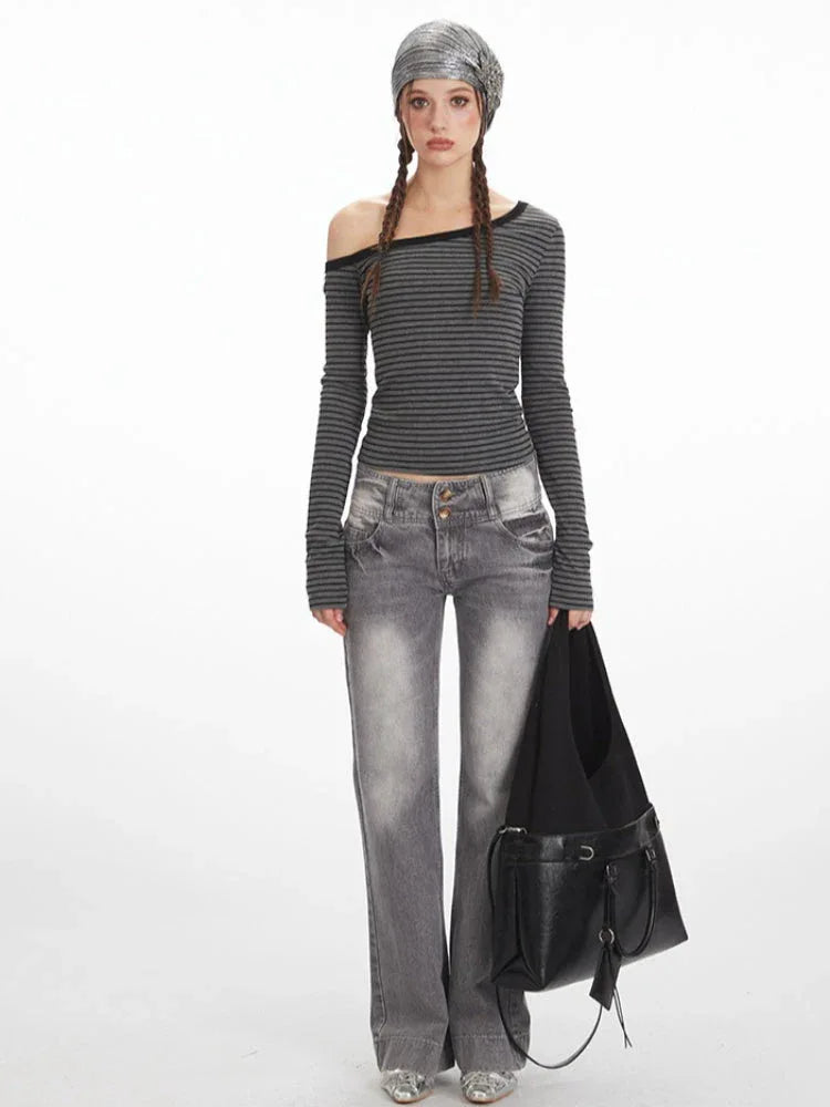 Woman wearing a grey and black striped off-the-shoulder long sleeve top and grey wash jeans, holding a black handbag. Main image