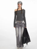 Woman wearing a grey and black striped off-the-shoulder long sleeve top and grey wash jeans, holding a black handbag.