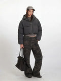 Side profile of a woman modeling the grey cropped puffer jacket and camouflage pants.