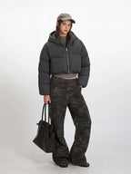 Side profile of a woman modeling the grey cropped puffer jacket and camouflage pants.