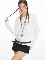 Close-up of a model wearing a white long-sleeve top, black shorts, and a heart pendant.