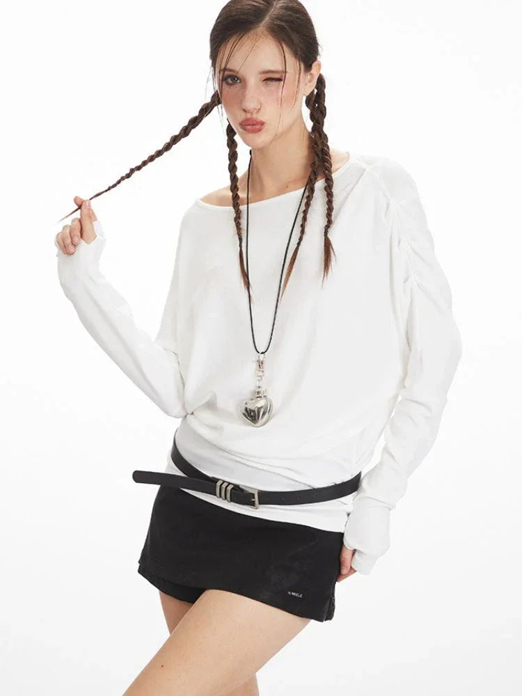 Close-up of a model wearing a white long-sleeve top, black shorts, and a heart pendant.