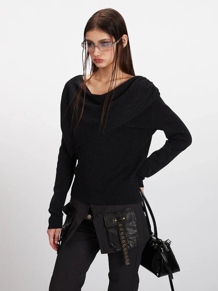 Close-up of a woman wearing a black long-sleeve asymmetrical knit sweater