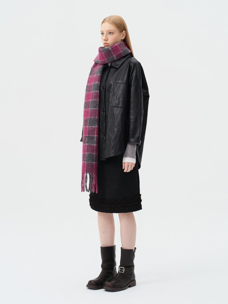 Woman wearing a black leather jacket, black skirt, and a pink and grey plaid scarf.