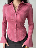 Woman wearing a pink striped long-sleeve collared shirt with flared cuffs.